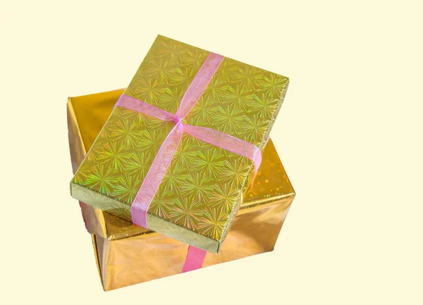 Envuelto en lámina de oro, dos cajas de regalo atadas con cinta roja y apiladas, aisladas sobre un fondo amarillo — Foto de Stock