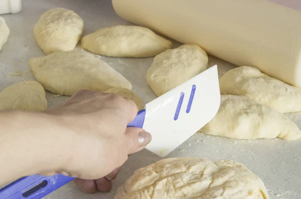 Les mains des femmes pétrissent la pâte et font cuire des tartes sur une table saupoudrée de farine — Photo