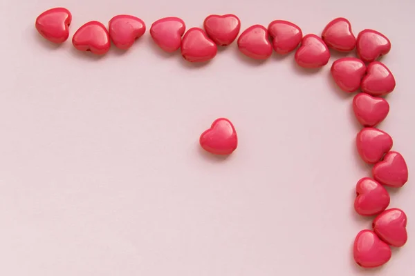 Czerwone koraliki w kształcie serca znajdują się w prawym górnym rogu na różowym tle, makiety do projektowania — Zdjęcie stockowe