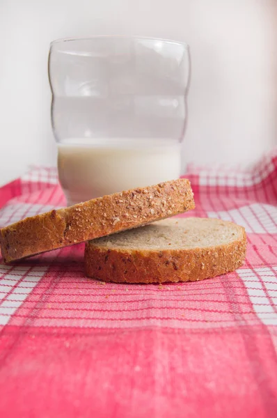 Close-up of Sliced rye bread and a glass of milk on a cloth red napkin, rustic background, healthy food, vertical shot