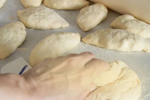 Las manos de las mujeres amasan la masa y cocinan pasteles sobre una mesa espolvoreada con harina —  Fotos de Stock