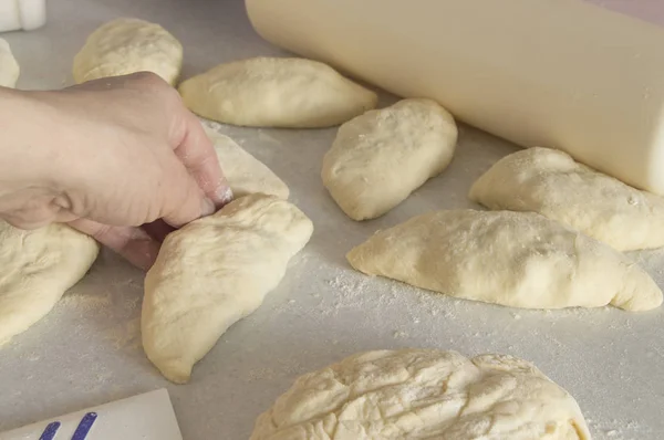 Las manos de las mujeres amasan la masa y cocinan pasteles sobre una mesa espolvoreada con harina —  Fotos de Stock