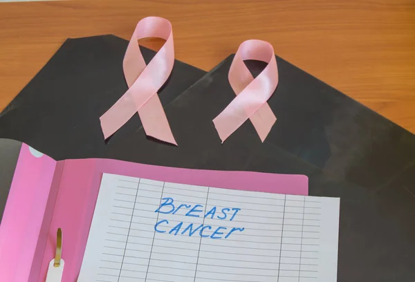 X-rays, two pink ribbons and a pink file folder lie on the table as a symbol of breast cancer awareness and prevention