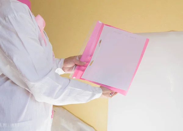 Female doctor in pink blouse and white coat demonstrates awareness in breast cancer prevention and health information