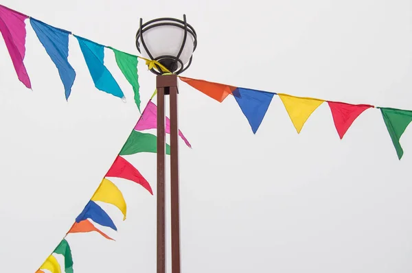 Πολύχρωμα τριγωνικές σημαίες πανί κρέμονται σε σχοινιά δεμένα σε μια κολώνα, διακόσμηση για το φεστιβάλ, καρναβάλι, διακοπές — Φωτογραφία Αρχείου