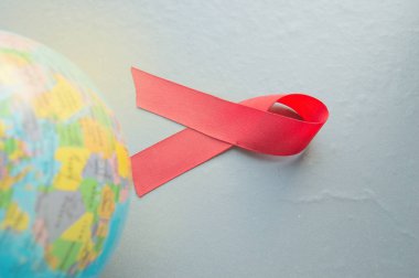 Dünyanın arka planda kırmızı kurdele mücadele, şefkat, destek ve Aids olmadan bir gelecek için umut sembolü uluslararası bir sembolüdür