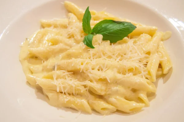 Pasta Penne quattro formaggi con basilico, primo piano, ricetta tradizionale italiana, vista dall'alto — Foto Stock