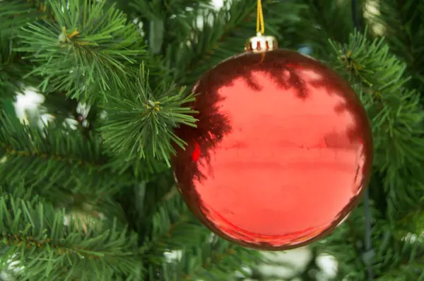 Leuchtend rote Kugel auf künstlichem Weihnachtsbaum, Weihnachtsdekoration, Neujahrshintergrund — Stockfoto