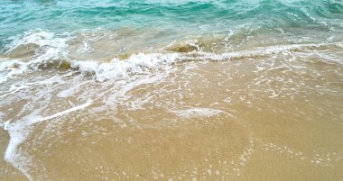 Palma de Mallorca sahilinin altın kumu üzerinde mavi bir deniz dalgasının beyaz köpüğü..