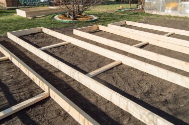 Wooden formwork from new boards for vegetable beds in the garden, preparation and construction, carpentry. clipart