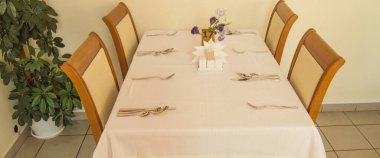 Otel restoranında masa örtüsü ve çatal bıçak takımı olan şenlik masası misafirleri bekliyor..