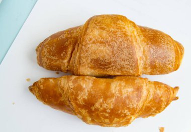 İki yeni pişmiş kruvasan, beyaz arka plan, üst manzara..