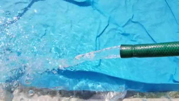 El agua fluye desde la manguera hacia la piscina inflable de llenado. Día soleado de verano, al aire libre — Vídeos de Stock