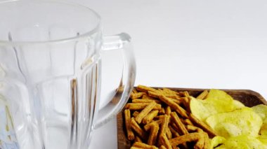 Tabağın arka planına kraker ve cips dolu cam bardağa bira dökmek.