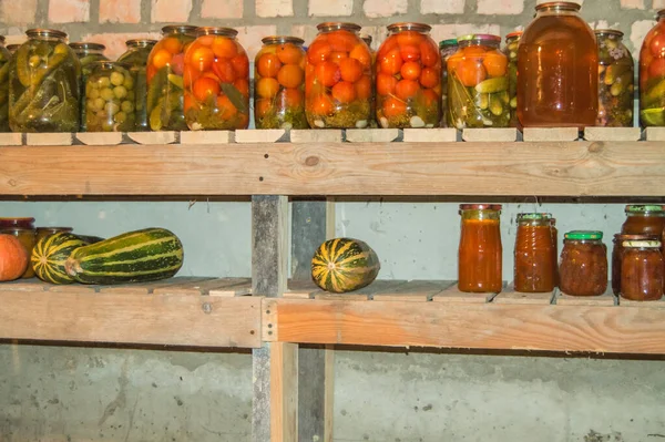 Kilerdeki bir rafta konserve sebze, meyve ve böğürtlen depolamak için cam kavanozlar, organik sebzelerin korunması.