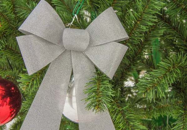 Traditionella dekorerade silverbågar hänger på de gröna grenarna av ett tallar, närbild. Julgransdekoration — Stockfoto