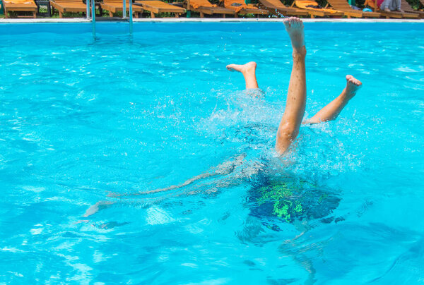 Дети ноги в воздухе в бассейне, весело ныряя подростки.