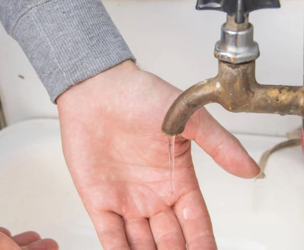 A man washes his hands with tap water from an old authentic copper tap, summer, outdoor, close-up.