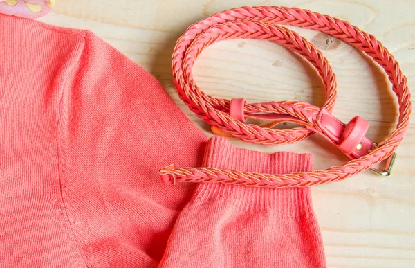 Women fashion pink sweater with a belt on light wooden background