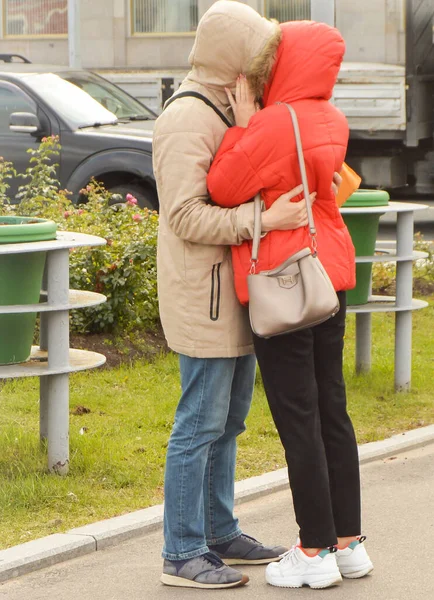 Un hombre y una mujer que se aman están de pie en una calle de la ciudad, abrazándose y besándose, sus rostros no son visibles — Foto de Stock