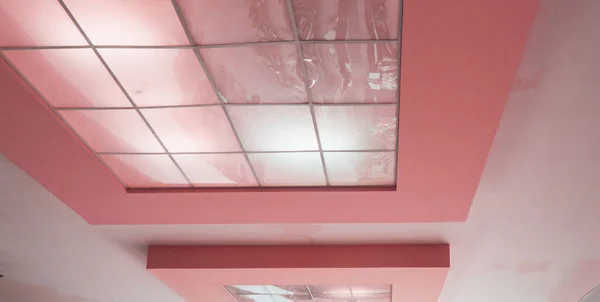 Pink ceiling with reflective tiles in a modern office space, conference room design