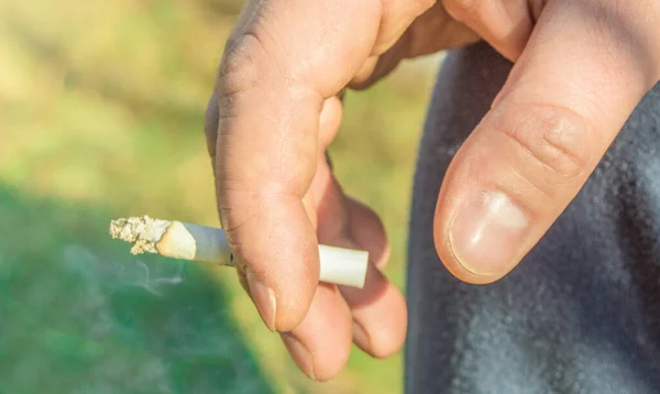 Detailní záběr staršího muže ruku Kouření cigarety, venku, v letní den — Stock fotografie