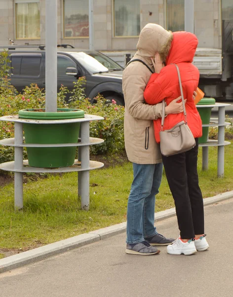 A man and a woman who love each other are standing on a city street, hugging and kissing, their faces are not visible — Stock Photo, Image