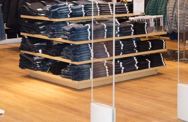 Jeans are stacked on the counter in a clothing store.