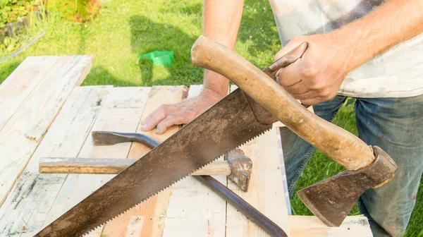 男はあなたの庭で建設作業のためにハックソー ハチェット 爪ハンマーを使用しています — ストック写真