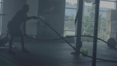 Spor salonunda çapraz fit antrenman yapan adam, halatlarla egzersiz yapıyor