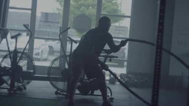 Spor salonunda çapraz fit antrenman yapan adam, halatlarla egzersiz yapıyor