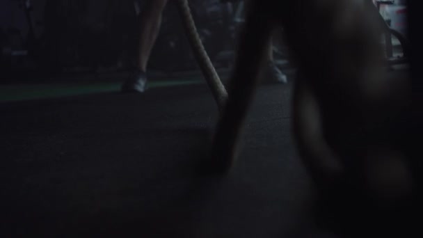 Homme faisant de la musculation au gymnase, des exercices avec des cordes 