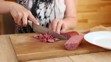 Sosisi bıçakla küçük parçalara ayır. Sosisli salata hazırla..