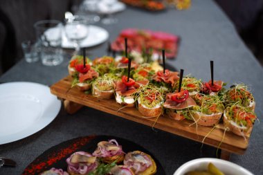 Tahta tepside peynirli, jambonlu, domatesli ve otlu sandviçler..