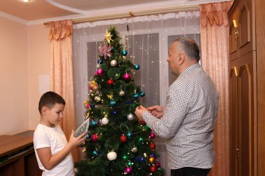 Baba oğul Noel ağacı süslüyorlar. Yılbaşı ve Noel tatili.