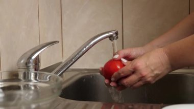 Domatesler mutfakta akan suyun altında yıkanır.