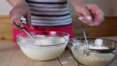 Bir kadın hamuru ekşi krema, yumurta ve un ile hazırlar ve karışımı karıştırır.
