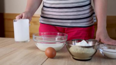 Bir kadın hamuru ekşi krema, yumurta ve un ile hazırlar ve karışımı karıştırır.
