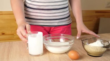 Bir kadın hamuru ekşi krema, yumurta ve un ile hazırlar ve karışımı karıştırır.