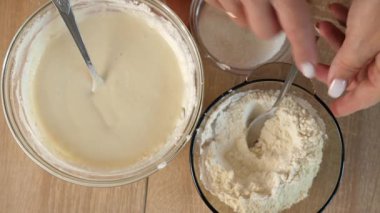 Bir kadın hamuru ekşi krema, yumurta ve un ile hazırlar ve karışımı karıştırır.