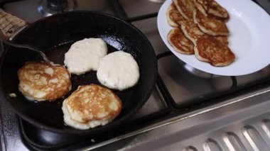 Bir kaşık sıcak tavaya altın kreplerle vururken, bir tabak taze pişmiş börek tutar..