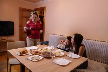 Kadın masaya bir sürahi Uzvar getiriyor, aile ikram bekliyor..