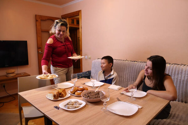 Woman sets plates with dishes on table during family holiday celebration.