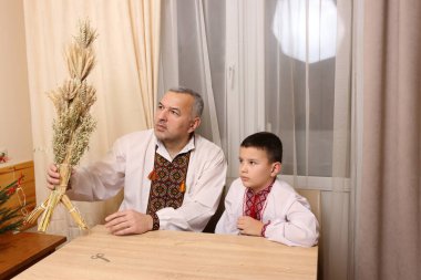 Nakışlı gömlekli bir adam Ukrayna bayram geleneğinin sembolü olan didukh taşıyor..