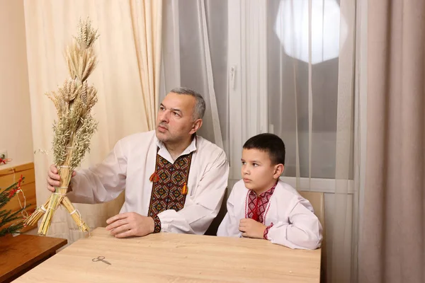 Nakışlı gömlekli bir adam Ukrayna bayram geleneğinin sembolü olan didukh taşıyor..