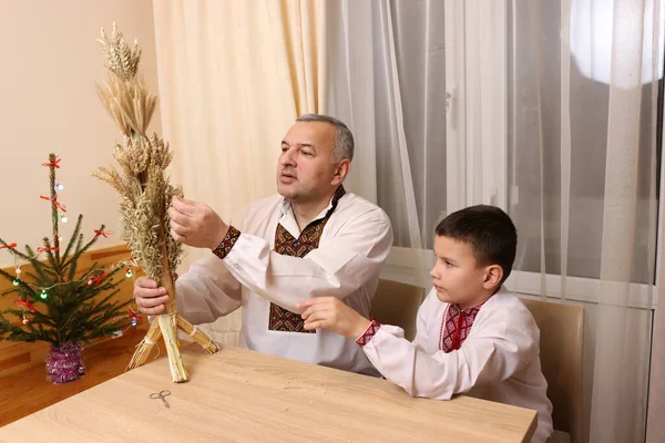 Nakışlı gömlekli bir adam sunar. Buğday sapından yapılmış uzun didük. Geleneksel Ukrayna Noel sembolü..