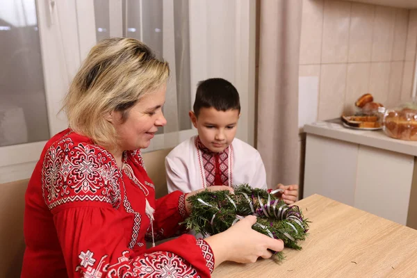 Nakışlı elbiseli bir kadın yeni yıl çelenginde birlikte çalışır..