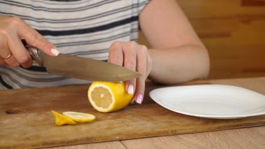 Tahta üzerinde limonu ince yuvarlak parçalara ayıran kadın, çay ya da aşçılık için hazırlıyor..
