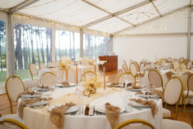 Süslü düğün salonu yuvarlak masalar, tel lambalar ve çiçek aranjmanları..