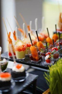 Açık kaplarda mini çerezler: karides, sebze ve şiş üzerinde peynir topları.